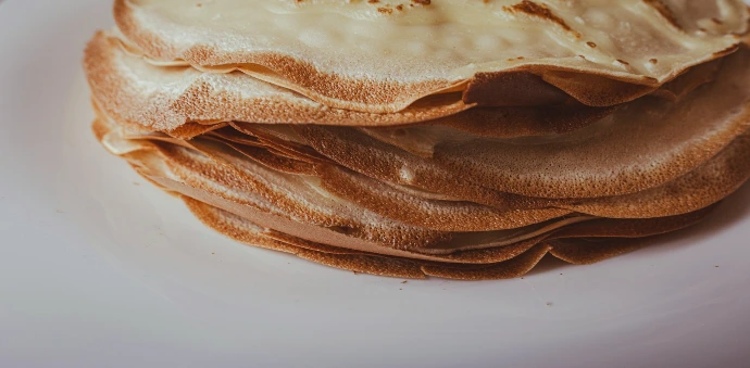 A white plate topped with pancakes covered in frosting